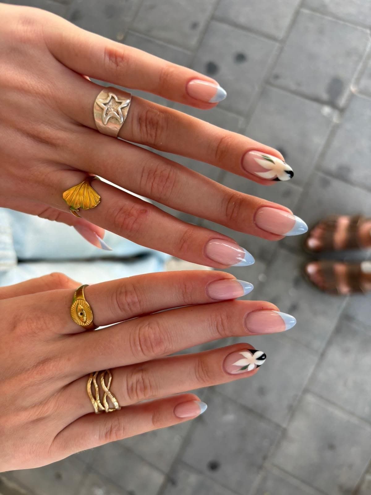 Francesa larga en azul claro con dos uñas decoradas con flores blancas sobre punta negra